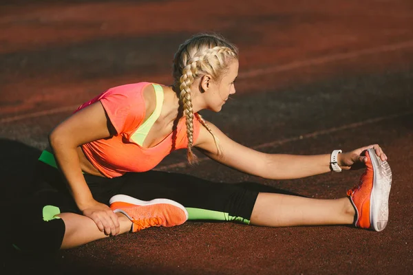 Jonge fitness vrouw is stretching in stadion — Stockfoto