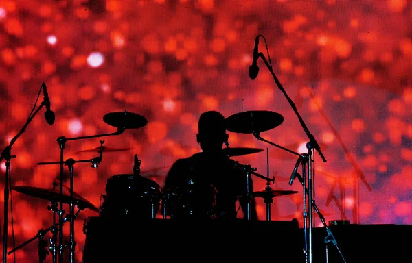 後ろの赤いパターン画面に対して音楽コンサートでドラマーのシルエット — ストック写真