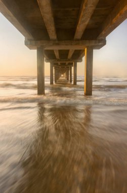 Classic view of the underneath side of the fishing pier at sunrise clipart