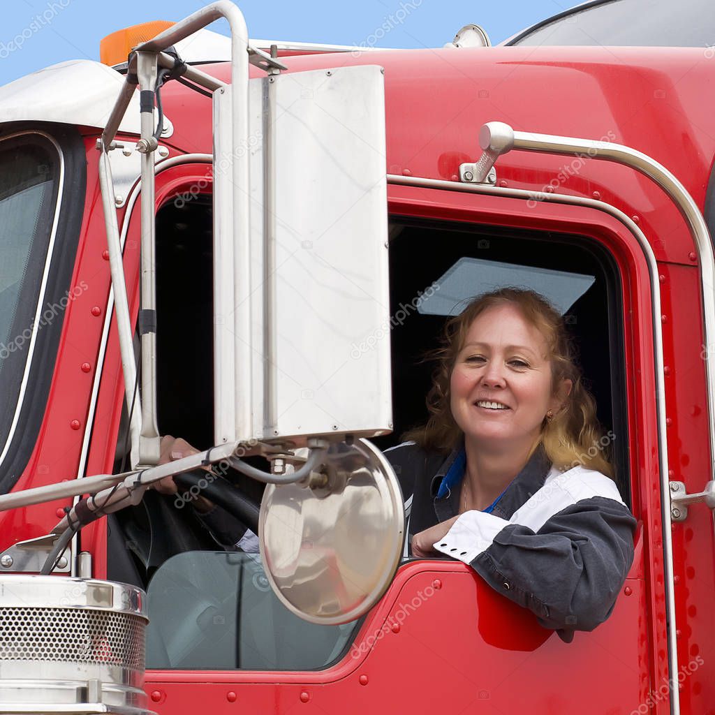 Woman truck driver looking out of a semi-truck while driving.