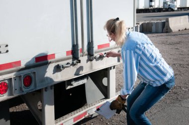 Woman truck driver checking her trailer seal number clipart