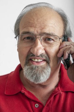 Kulağına cep telefonu dayanmış yaşlı bir adam.