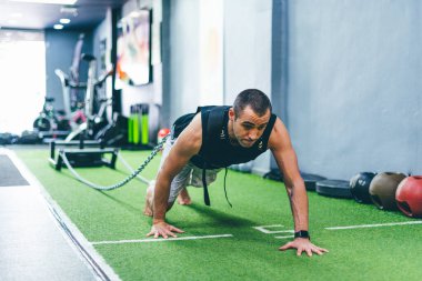 Latin çocuk spor salonunda kızağı ağırlıkla sürüklüyor. Eğitim kavramı