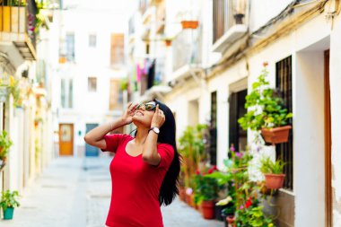 Genç esmer kız güneş gözlüğünü ayarlıyor. İki eli de Avrupa 'nın Bukolik sokağına bakıyor. şehir turizmi kavramı