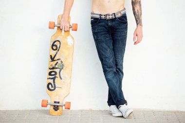 Beyaz duvarda uzun tahtası olan genç bir adamın kolları ve bacakları.