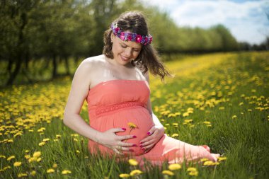 Bahar bahçe çiçek açan dandelions arasında güzel hamile kadın