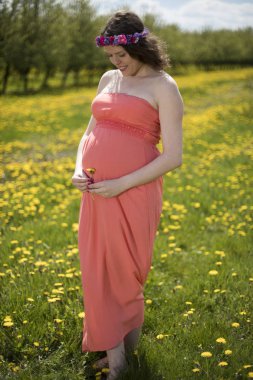 Bahar bahçe çiçek açan dandelions arasında güzel hamile kadın