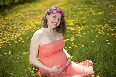 Bahar bahçe çiçek açan dandelions arasında güzel hamile kadın