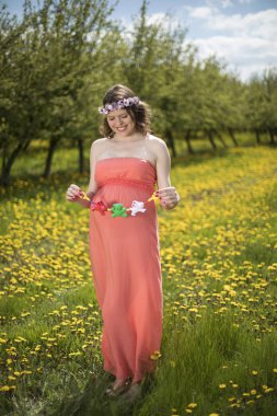 Bahar bahçe çiçek açan dandelions arasında güzel hamile kadın