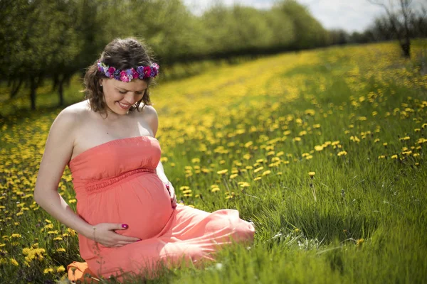 Bahar bahçe çiçek açan dandelions arasında güzel hamile kadın