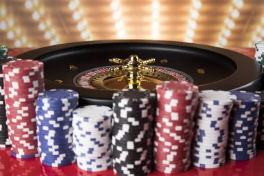 Kumar masasında poker fişleri, hareket halindeki rulet çarkı, kumarhane geçmişi