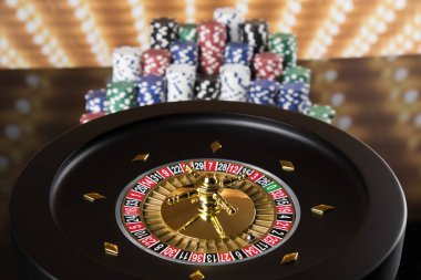Kumar masasında poker fişleri, hareket halindeki rulet çarkı, kumarhane geçmişi