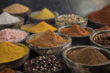 Mutfak masasında çeşitli baharatlar ve otlar var.