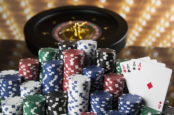 Poker Chips on gaming table, roulette wheel in motion, casino background