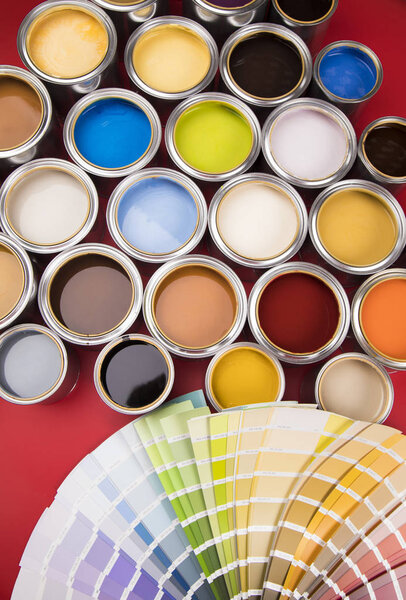 Открытые ведра с краской и кистью, красный фон
