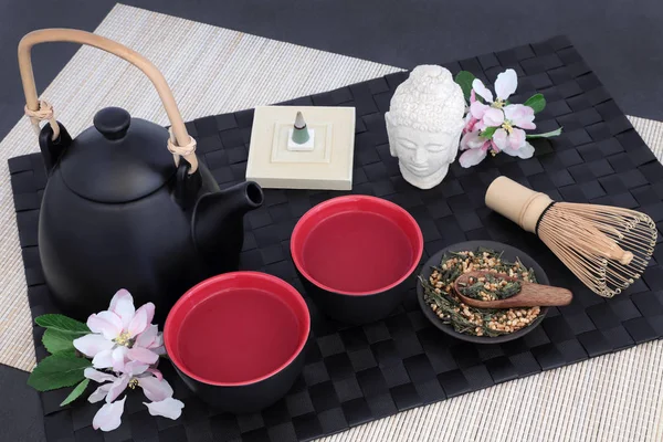 東洋のティーポット カップ 泡立て器 乾燥日本玄米茶藤山茶葉 花やお香黒マット スレートの背景 — ストック写真