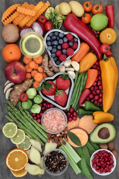 Health food for fitness concept with fresh fruit, vegetables, herbs, spices, nuts, himalayan salt and olive oil. High in antioxidants, fiber, smart carbohydrates, anthocyanins, minerals and vitamins.