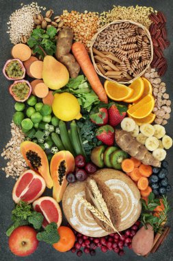 High fibre health food concept with fresh whole grain rye bread, cereals, grains, fruit, vegetables, nuts, legumes, herbs and spices. Foods high in omega 3, antioxidants, anthocyanins and vitamins. Rustic background on marble, top view. clipart