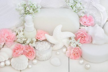 Gelin spa ve güzellik bakımı ve temizlik ürünleri ile foliating tuz, deniz kabuğu sabunlar, vücut losyonu, süngerler, yıkama bezler ile dekoratif kabukları ve inci beyaz ahşap zemin üzerinde eski karanfil çiçek.