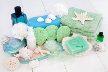 Spa ve banyo güzellik tedavi aksesuarları ile çay ağacı sabunlar, vücut losyonu, mavi banyo köpüğü, Aromaterapi uçucu yağ, süngerler, yıkama bezler, bodur ve banyo tuzları ile beyaz ahşap zemin üzerinde dekoratif deniz kabuklarını foliating ex.