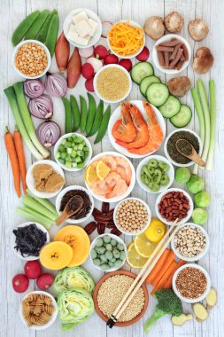 Macrobiotic food concept with seafood, miso paste, tofu, kuchika tea, wasabi nuts, vegetables, whole wheat pasta, legumes and grains with foods high in protein, antioxidants, vitamins and minerals. On rustic background with chopsticks, top view. clipart