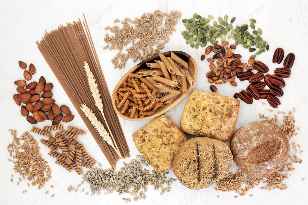 High fiber health food with whole grain bread rolls, whole wheat pasta, nuts, seeds and grains. Rustic background on rustic wood, top view. Foods high in omega 3, antioxidants and vitamins.