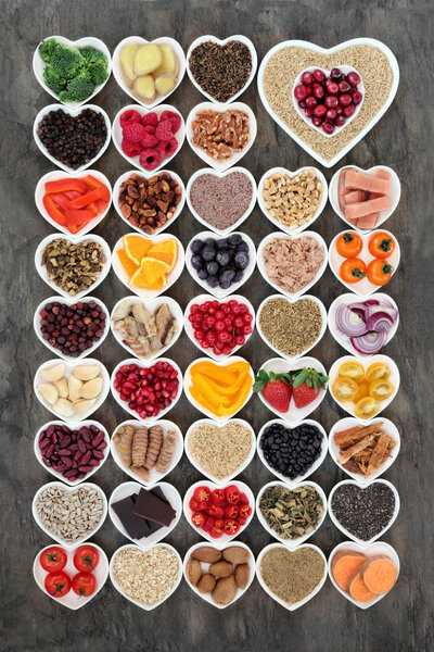 Super food for a healthy heart concept with health foods of fish, fruit, vegetables, pulses, nuts, seeds, grains, cereals with herbs and spice used in alternative herbal medicine. Foods high in omerga 3, antioxidants, anthocyanins and vitamins.