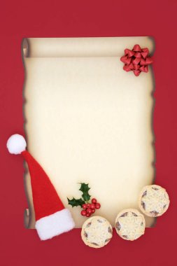 Noel Baba'ya mektup kırmızı zemin üzerine boş parşömen kağıt, santa şapka, kıymalı börek, yay ve holly berry yaprak sapı ile. Noel arifesi kavramı.