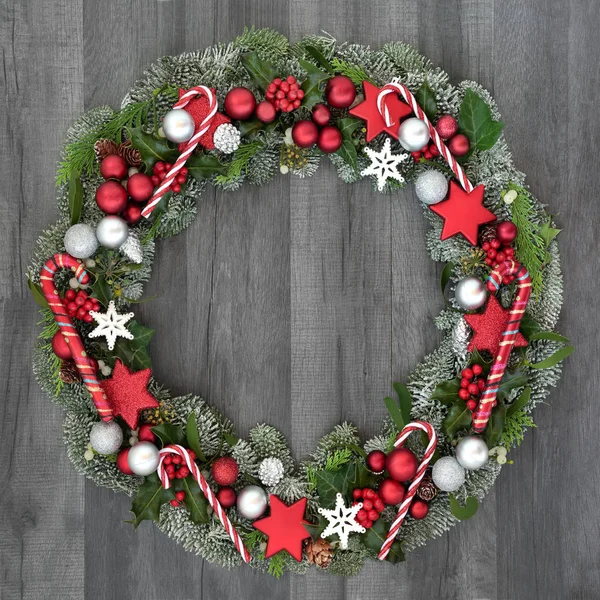 キャンディーと安物の宝石の装飾 ヒイラギ ヤドリギ アイビー 素朴なグレー ウッドの背景に小ぎれいななもみとクリスマスと冬の花輪 — ストック写真