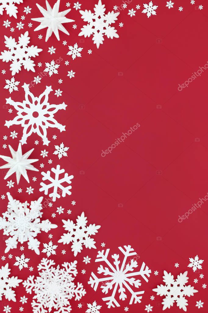 White snowflake decorations forming a Christmas abstract background border on red. Traditional Christmas greeting card for the festive holiday season.