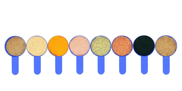 Body building food supplement powders in blue scoops. Gymnema sylvestre, pea protein, turmeric, chocolate whey, wheatgrass, cacao, chlorella and hemp powder, left to right. On white background with copy space.