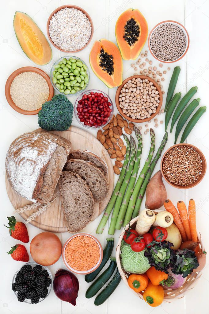 Healthy high fibre food concept with fruit, vegetables, whole grain rye bread, legumes, grains and cereals on rustic white wood background. High in antioxidants, anthocyanins, vitamins and minerals.