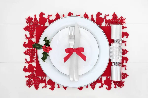 磁器の皿 カトラリー ダイヤモンド クラッカー 白の木のテーブルに赤いランチョン マットの冬ホリー クリスマス ディナー テーブルの設定 お祝いテーマの概念 — ストック写真