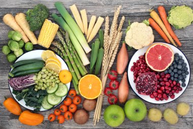 High fibre super food concept with fresh fruit and vegetables and wheat sheaths. High in anthocyanins, antioxidants, minerals  and vitamins. Top view on rustic wood background. clipart