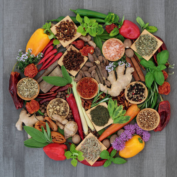 Spice and herb food seasoning collection with fresh and dried spices and herbs forming a circle on rustic wood background. Top view.