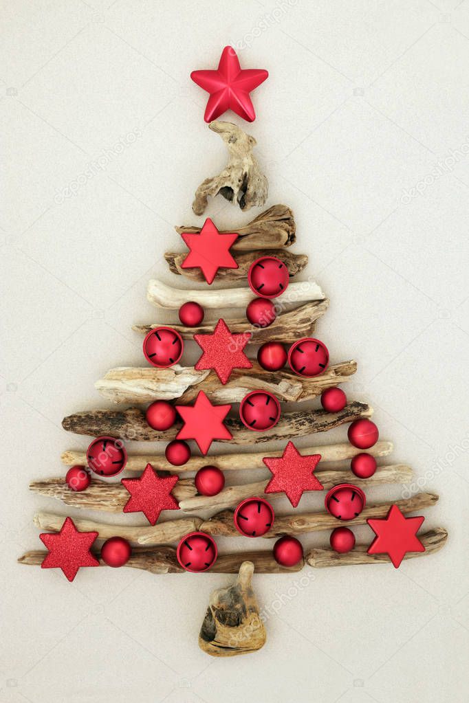 Abstract driftwood Christmas tree with red bauble star and bell decorations on mottled cream background. Christmas card for the festive holiday season.