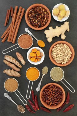 Spices for losing weight with turmeric, cumin, ginger, chilli, cinnamon and gymnema sylvestre used to suppress appetite. Top view on slate background. clipart