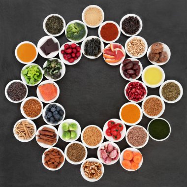 Sağlıklı gıda tekerlek gıdalar yavaş yaşlanma süreci ile meyve, sebze, balık, fındık, otlar, baharatlar, zeytinyağı, bal, ek tozlar, yeşil çay ve polen tahıl ile. Slate üzerinde üstten görünüm.