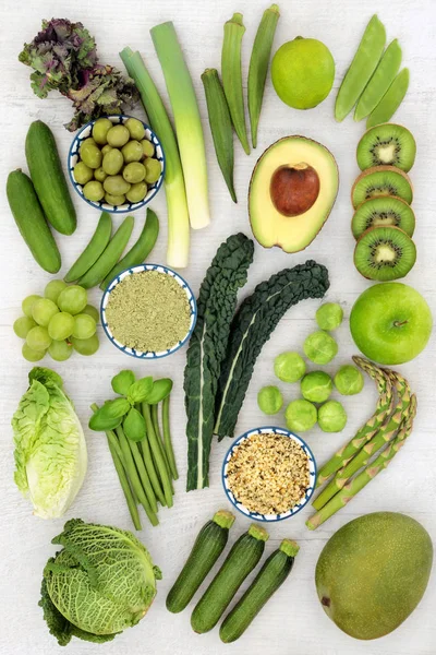 Healthy green fruit and vegetables with wheatgrass supplement powder and hemp husk seeds. Health foods high in antioxidants, vitamins, minerals and dietary fibre. Top view on rustic wood.