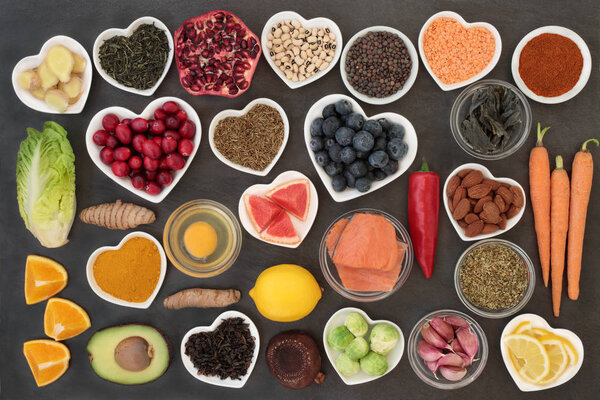 Superfood to slow the ageing process concept including fish, fruit, vegetables, nuts, green and black tea, herbs, spices and dairy. High in antioxidants, anthocyanins, dietary fibre and vitamins. Top view on slate.