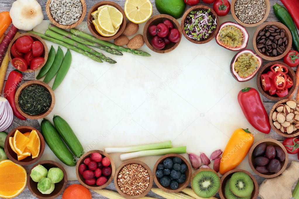 Healthy super food background border on parchment with fresh fish, fruit, vegetables, seeds, grains, nuts, herbs and spices. Very high in antioxidants, anthocyanins, vitamins and dietary fibre.Top view.
