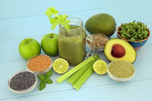 Health food diet smoothie drink with fresh fruit, vegetables, matcha powder, flax, chia and hemp  seed on blue wood background. High in omega 3, antioxidants, vitamins and dietary fibre.