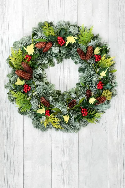 雪でクリスマスの自然の花輪は 素朴な白い木製のフロントドアの背景にモミ ホリー ミステリー 松のコーンをカバーしました クリスマス休暇シーズンと新年のための構成 — ストック写真
