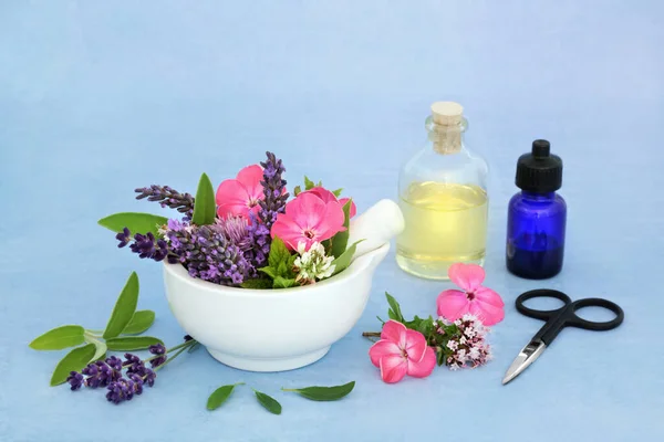 Herbal medicine preparation with flowers & herbs in a mortar with pestle & aromatherapy essential oil bottles. Still life for naturopathic health care concept.