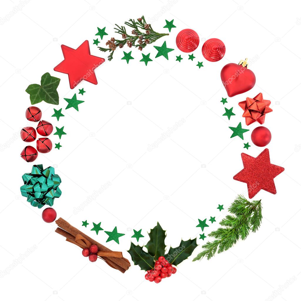 Christmas wreath with holly, winter greenery, red bauble decorations & green stars on white background. Minimal composition for the festive holiday season. Top view, flat lay, copy space.