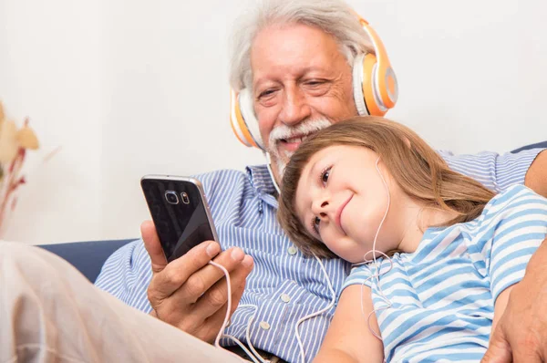 Abuelo Nieto Con Auriculares Escuchan Música Abrazándose Sofá — Foto de Stock