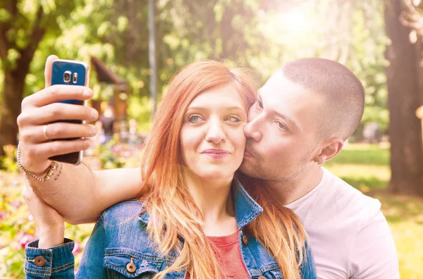 年轻夫妇与手机在公园做一个自拍 — 图库照片
