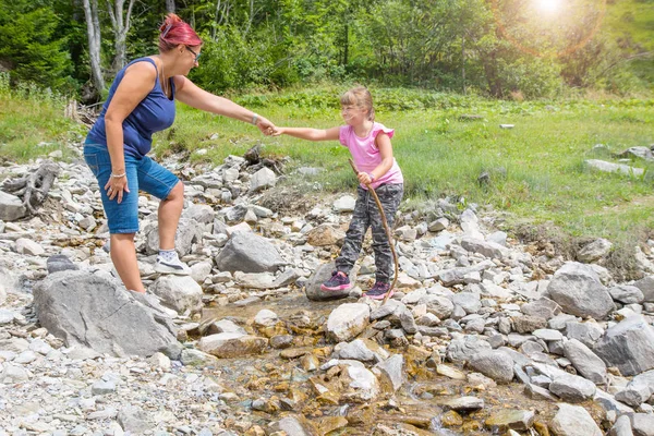 妈妈帮助她的女儿过山溪 — 图库照片