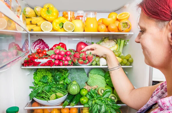 Donna Raccogliendo Frutta Sul Frigorifero Pieno — Foto Stock