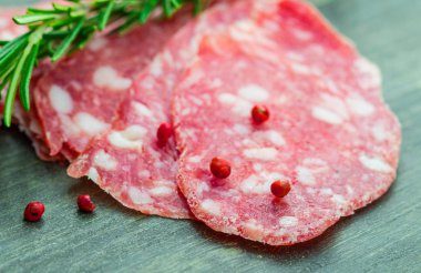 Ahşap üzerine siyah ve kırmızı biberli salam dilimleri